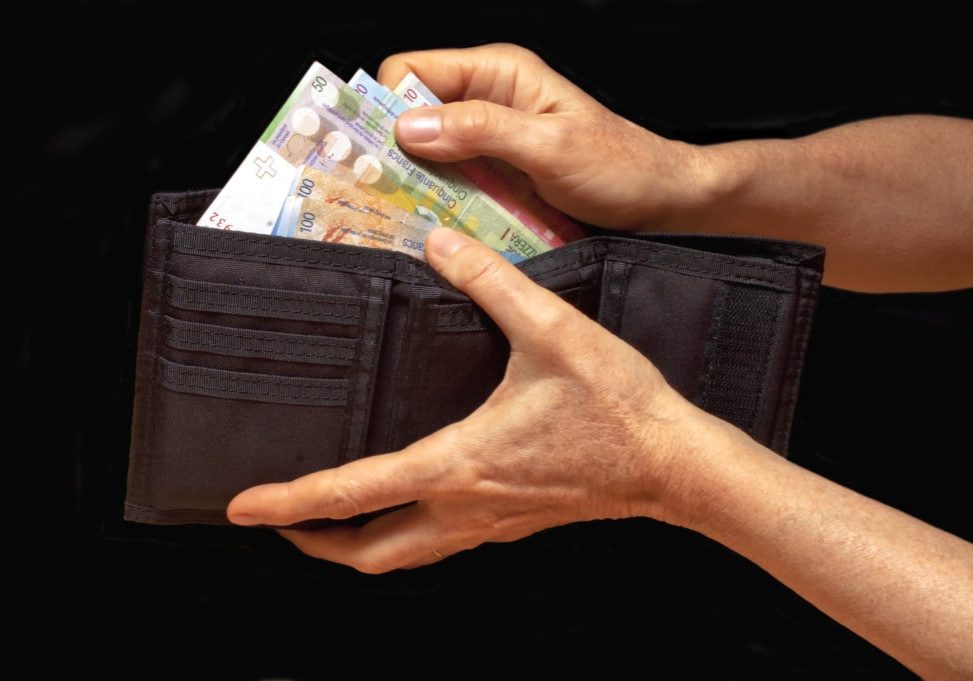 Black wallet with money in hands. Swiss francs banknotes.