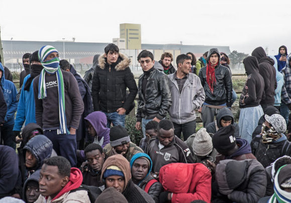 A,Group,Of,Migrants,And,Refugees,Wait,To,Leave,The
